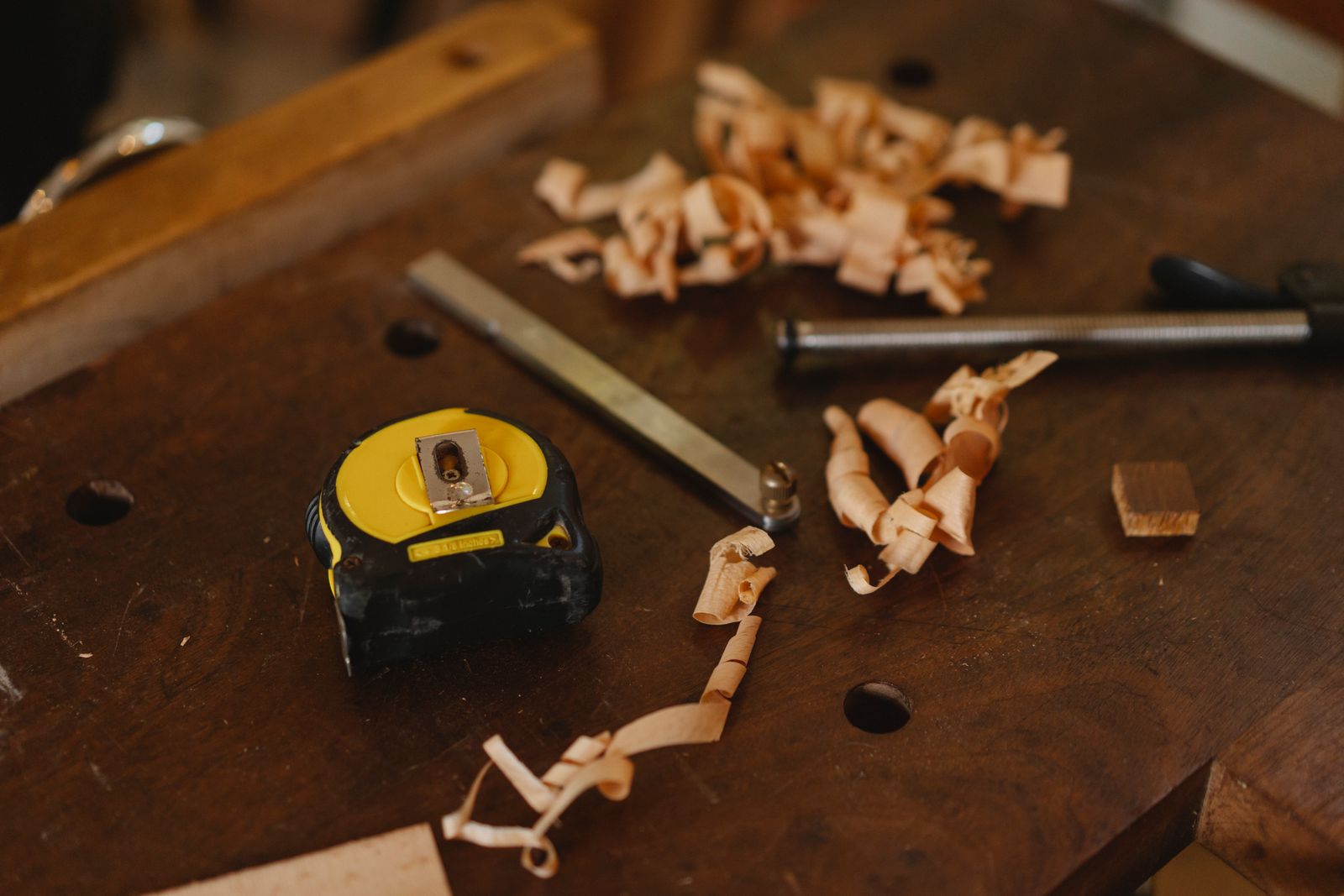 Établi de l'atelier avec mètre ruban, ciseau à bois et copeaux